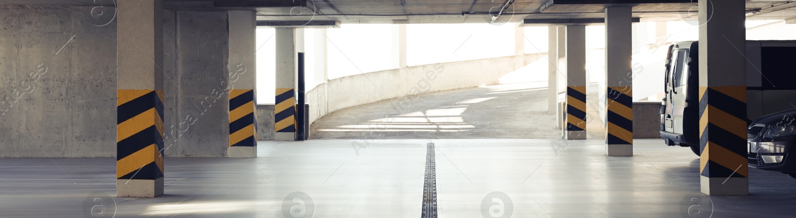 Image of Open car parking garage with ramp on sunny day, banner design