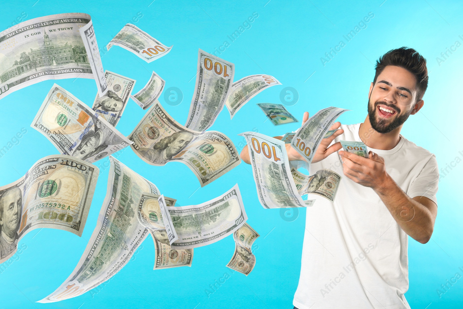 Image of Happy man throwing money on light blue background. Dollar bills flying away from him