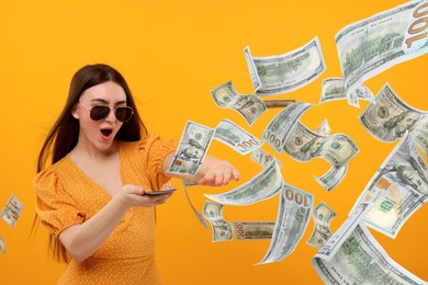 Image of Excited woman throwing money on orange background. Dollar bills flying away from her