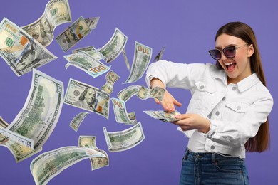 Image of Happy woman throwing money on dark violet background. Dollar bills flying away from her