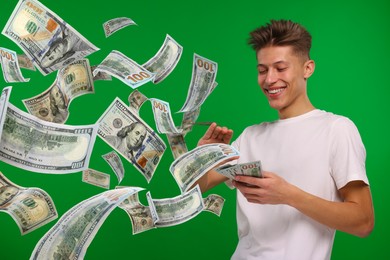 Happy man throwing money on green background. Dollar bills flying away from him