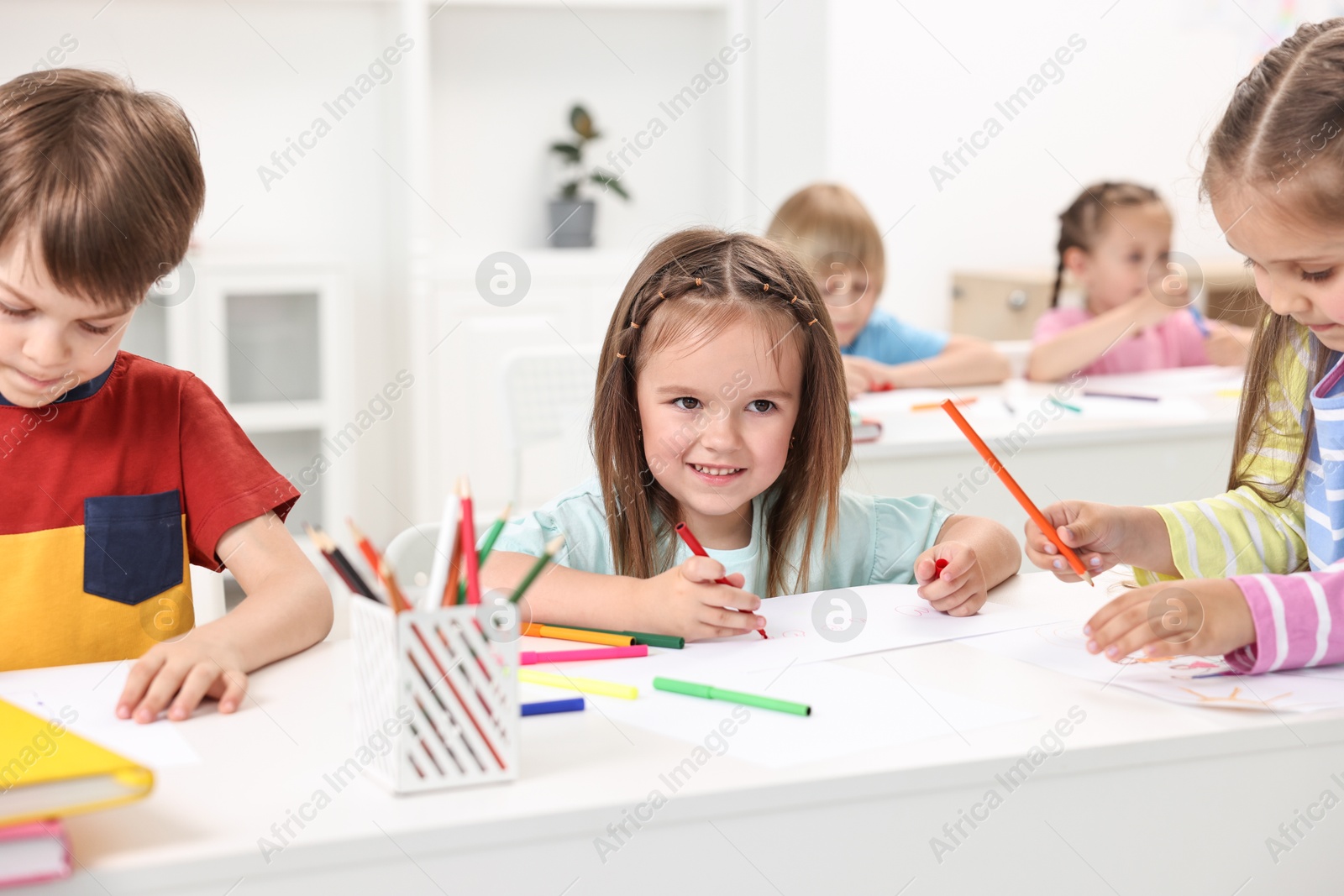 Photo of Group of children drawing at table indoors