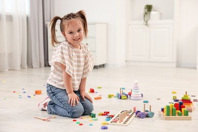 Photo of Cute little girl playing on floor indoors