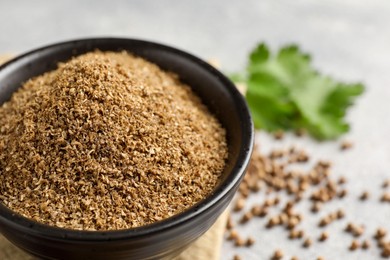 Photo of Coriander powder in bowl and seeds on table, closeup. Space for text