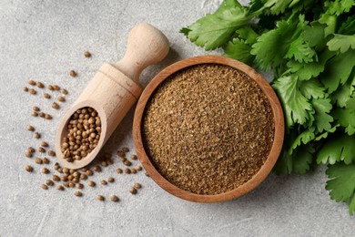 Coriander powder in bowl, seeds and green leaves on light grey table, top view