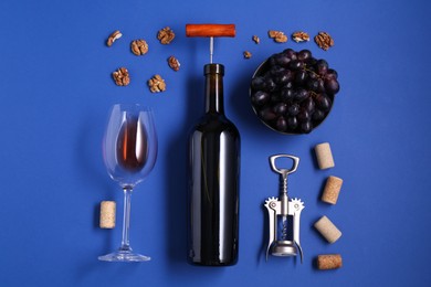 Photo of Flat lay composition of bottle with corkscrew and grapes on blue background