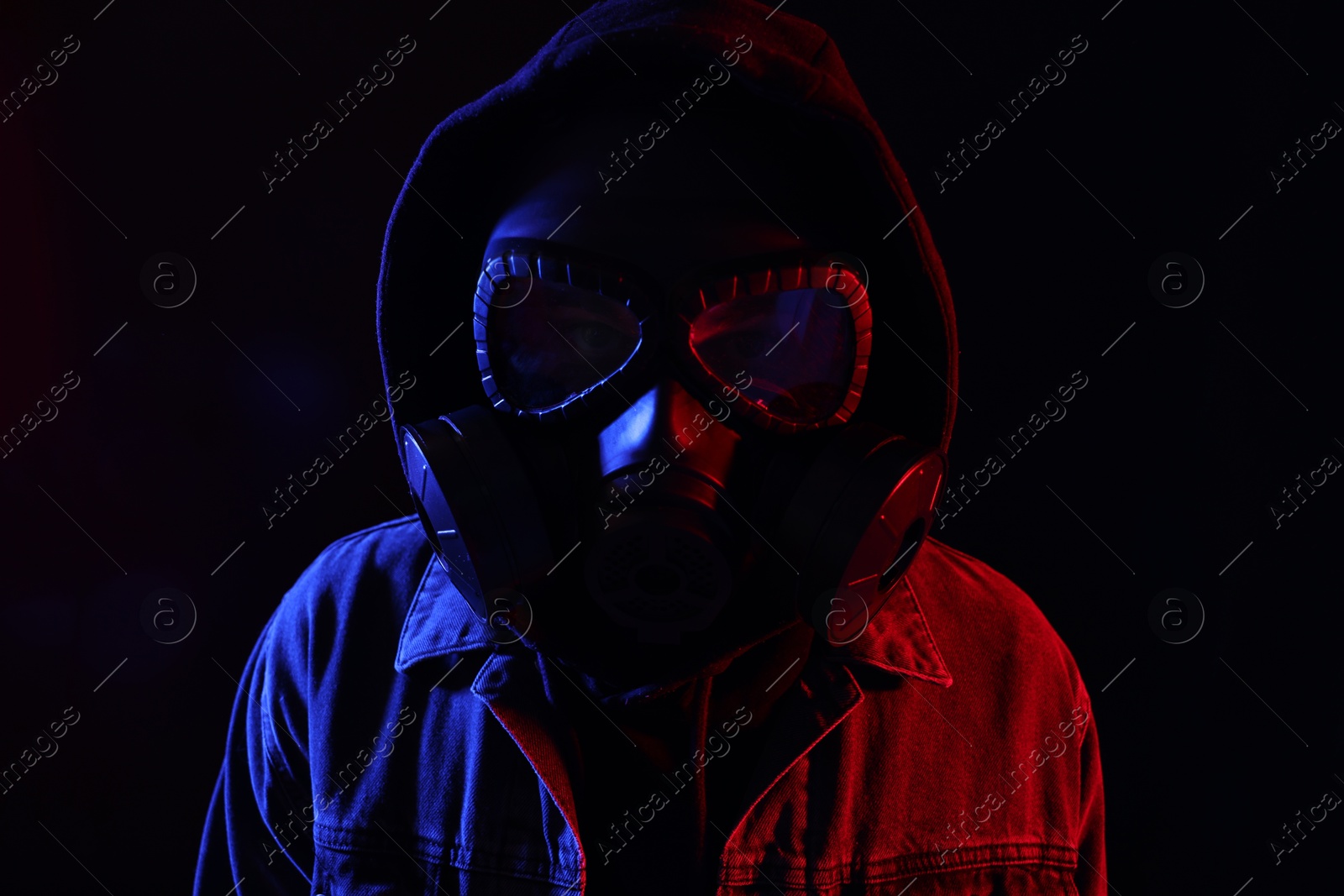 Photo of Man wearing gas mask in color lights on black background