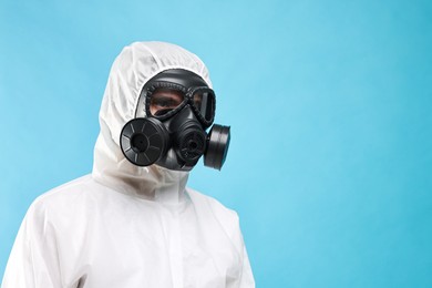 Worker in gas mask on light blue background, low angle view. Space for text