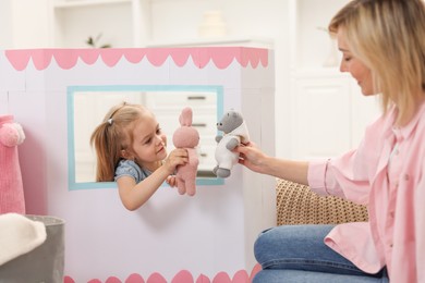 Puppet theatre. Girl playing toys with her mother at home