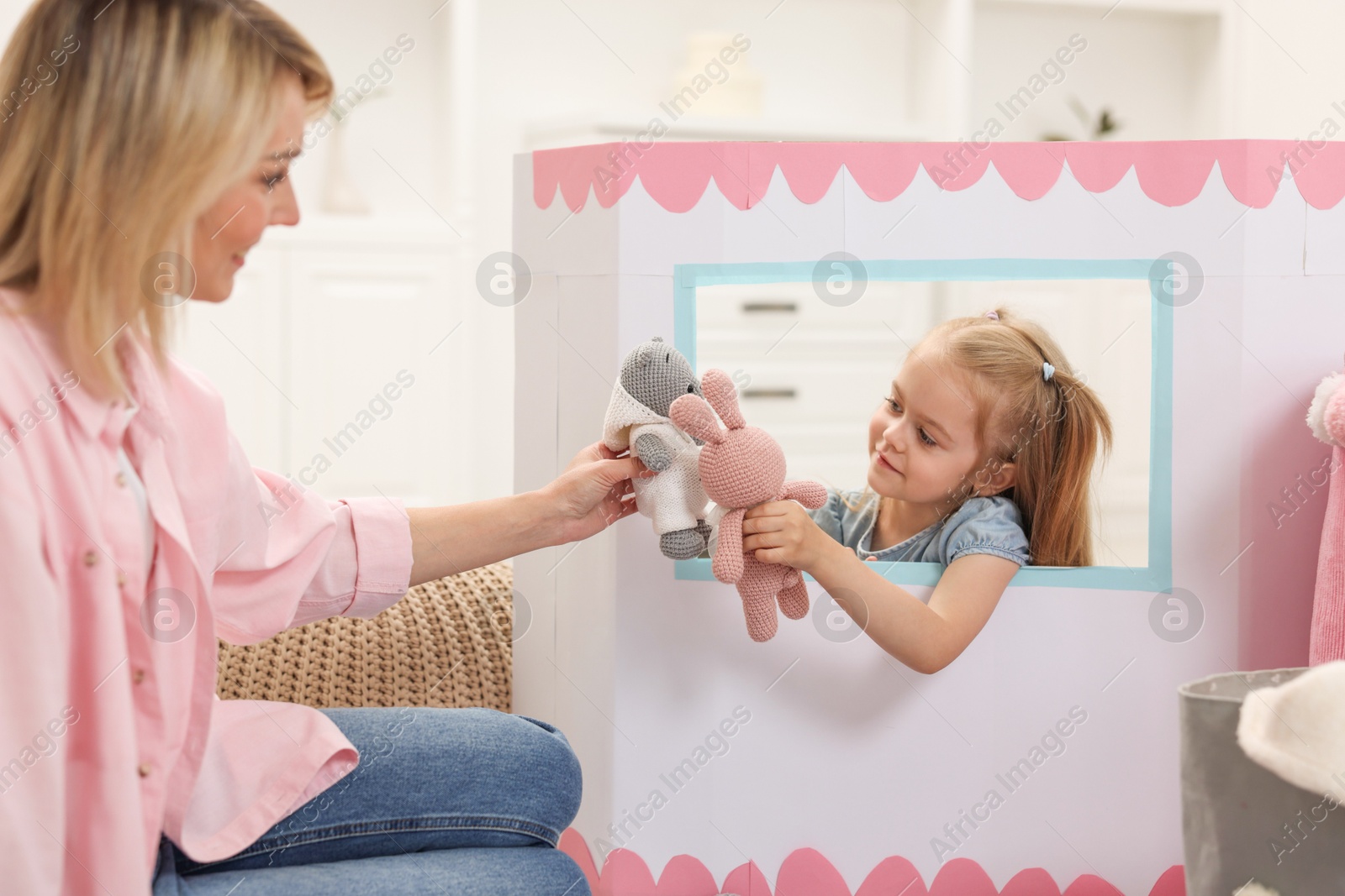 Photo of Puppet theatre. Girl playing toys with her mother at home