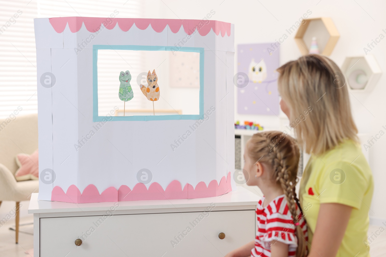 Photo of Mother and daughter watching puppet theatre at home