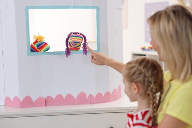 Mother and daughter watching puppet theatre at home