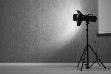 Grey photo background and professional lighting equipment in studio, space for text