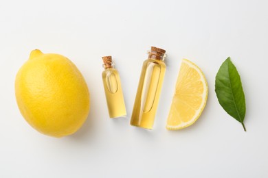 Photo of Bottles of essential oils, lemon and green leaf on white background, flat lay