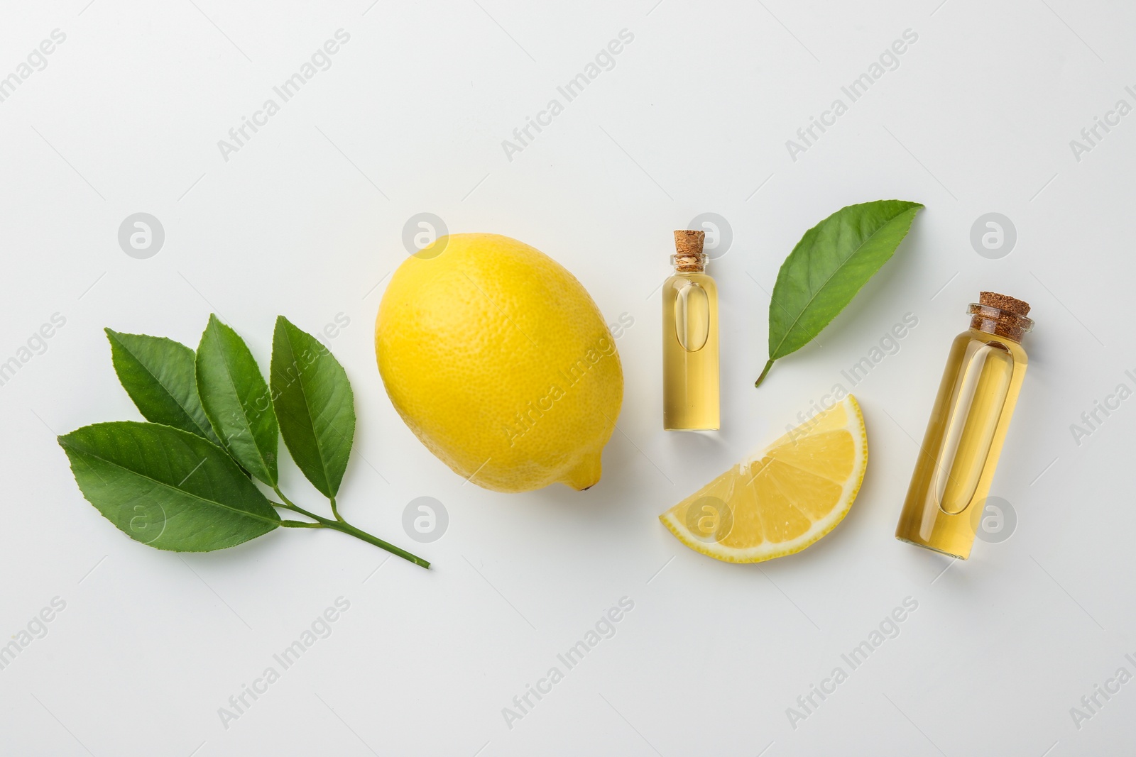 Photo of Bottles of essential oils, lemon and green leaves on white background, flat lay