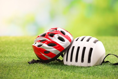 Two protective helmets on green grass, space for text