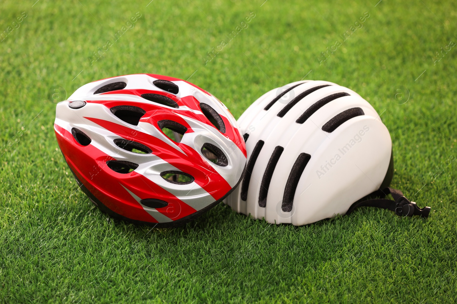 Photo of Two protective helmets on green grass. Sports equipment