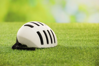 Photo of White protective helmet on green grass, space for text