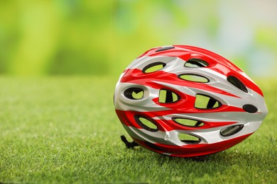 Colorful protective helmet on green grass, space for text