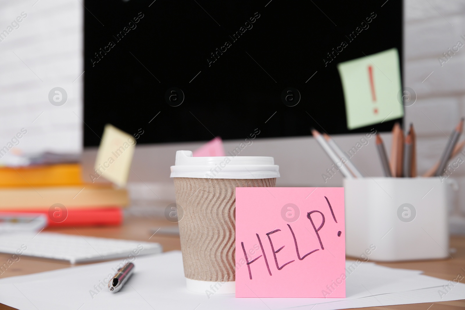 Photo of Note with word Help, cup and stationery on wooden table at workplace