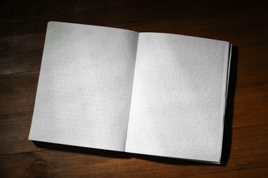 Photo of Book with Braille text on wooden table, top view. Education and leisure for blind people