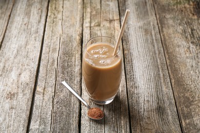 Photo of Delicious protein shake in glass and spoon with powder on wooden table