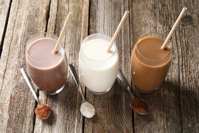 Photo of Delicious protein shakes in glasses and spoons with powder on wooden table