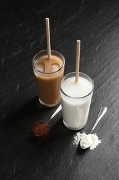 Photo of Delicious protein shakes in glasses and spoons with powder on black table