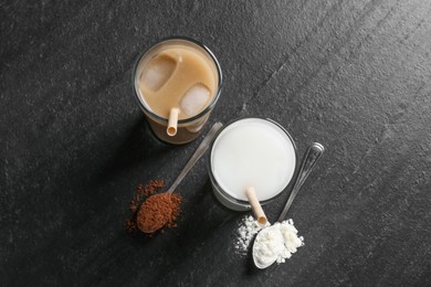 Photo of Delicious protein shakes in glasses and spoons with powder on black table, flat lay