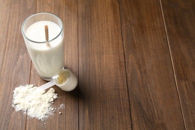 Photo of Delicious protein shake in glass, scoop and powder on wooden table, space for text