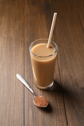 Photo of Delicious protein shake in glass and spoon with powder on wooden table