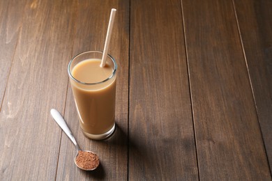 Photo of Delicious protein shake in glass and spoon with powder on wooden table, space for text