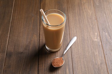 Photo of Delicious protein shake in glass and spoon with powder on wooden table