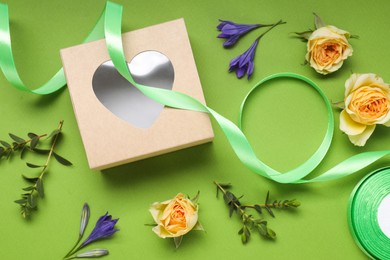 Flat lay composition with beautiful ribbon reel and gift box on green background