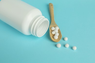 Homeopathy. Bottle and scoop with pills on light blue background