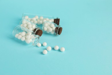 Photo of Homeopathy. Glass bottles with pills on light blue background, space for text