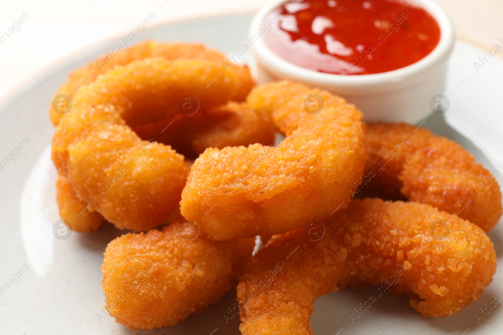 Photo of Tasty breaded fried shrimps and sauce on plate, closeup