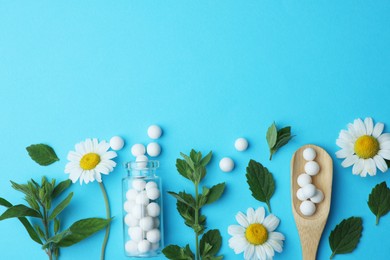 Homeopathy. Glass bottle, pills, chamomiles and green leaves on light blue background, flat lay. Space for text