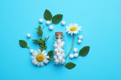 Homeopathy. Glass bottle, pills, chamomiles and green leaves on light blue background, flat lay