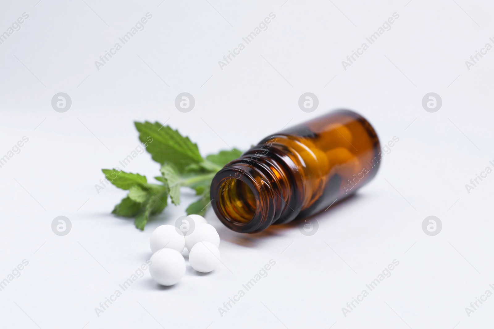 Photo of Homeopathy. Glass bottle, pills and mint on white background