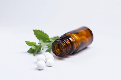 Homeopathy. Glass bottle, pills and mint on white background