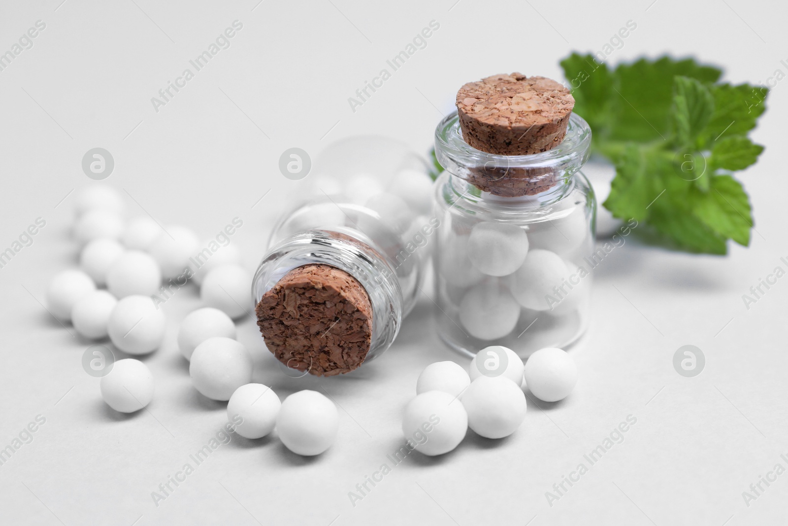 Photo of Homeopathy. Glass bottles, pills and mint on white background, closeup