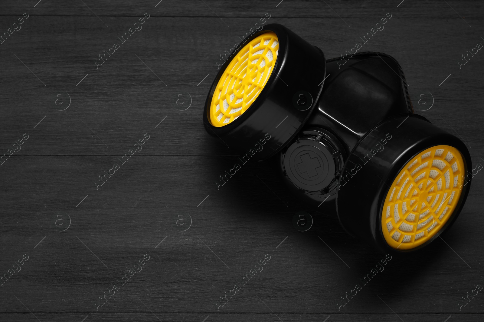 Photo of One respirator mask on black wooden background, top view. Space for text