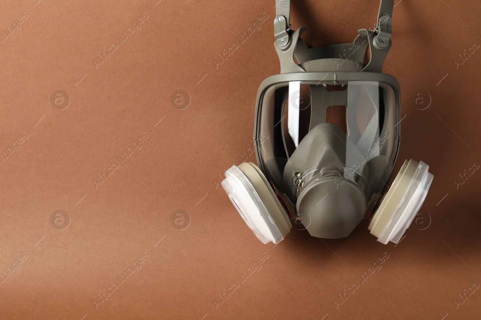 Photo of One respirator mask on brown background, top view. Space for text