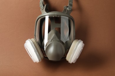 Photo of One respirator mask on brown background, top view