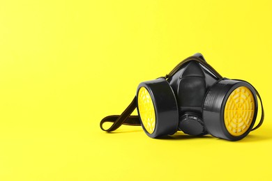 Photo of One respirator mask on yellow background, space for text