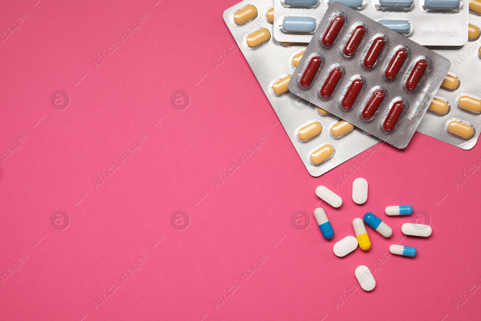 Photo of Different antibiotic pills in blisters on pink background, flat lay. Space for text