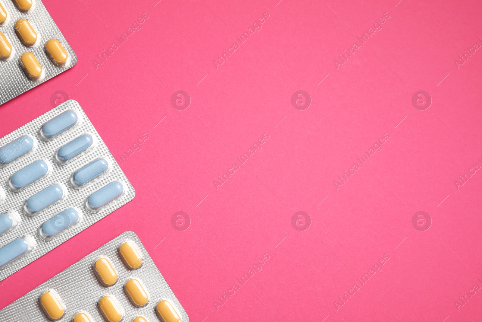 Photo of Different antibiotic pills in blisters on pink background, flat lay. Space for text