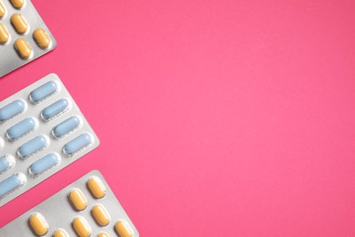 Different antibiotic pills in blisters on pink background, flat lay. Space for text