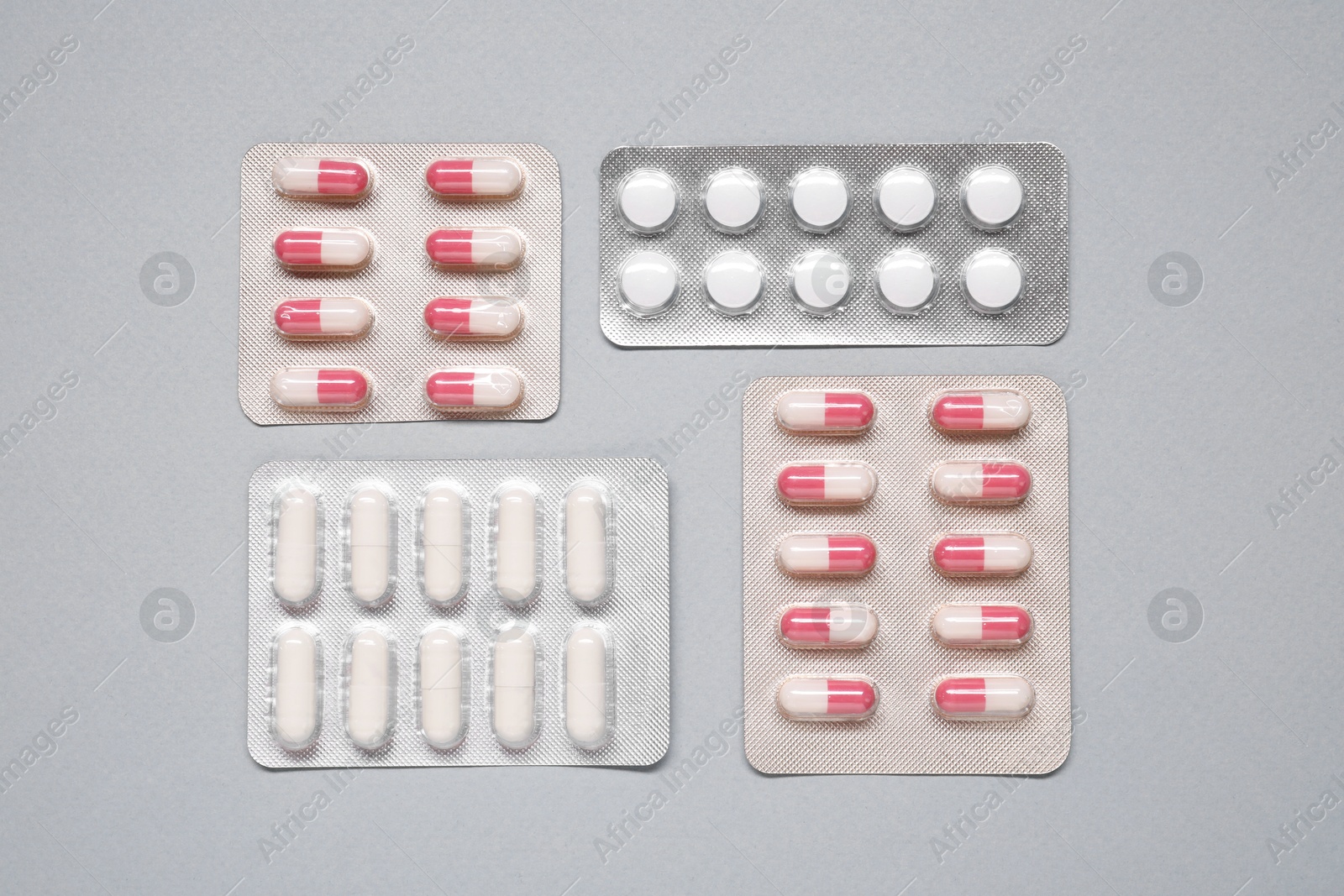 Photo of Different antibiotic pills in blisters on gray background, flat lay